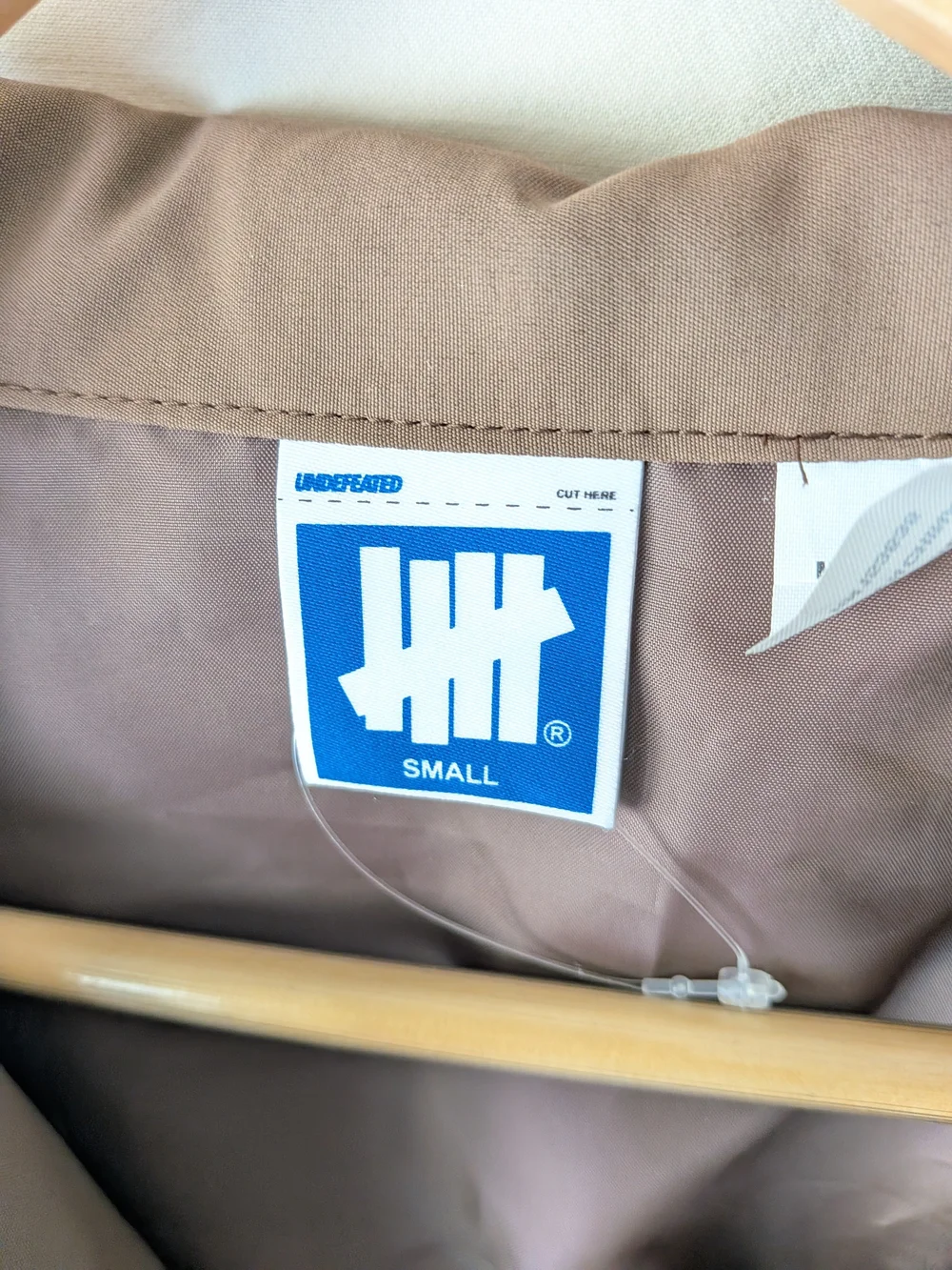 Undefeated Jacket in Taupe and Beige with Blue Logo Tag